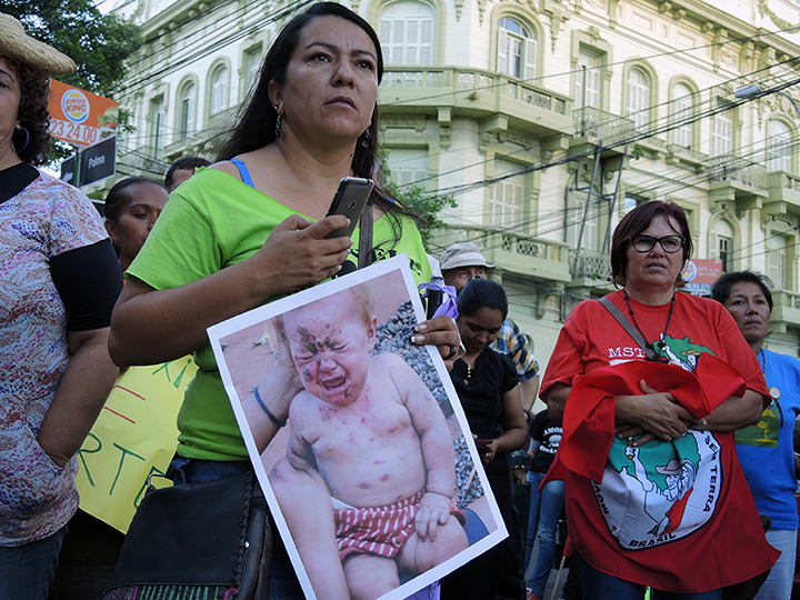 Woman holds photo of baby whose condition is blamed on agrotoxins, during rally in Asunción, Paraguay, 3 Dec 2014.  PhotoLangelle.org